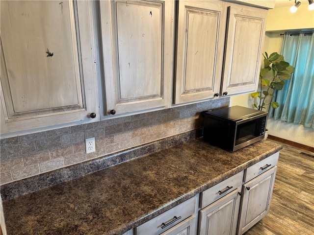 kitchen featuring stainless steel microwave, wood finished floors, baseboards, and backsplash