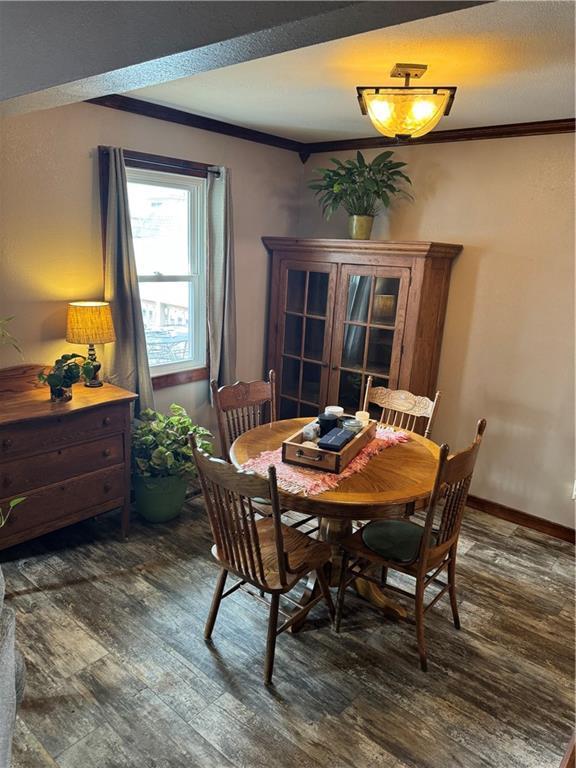 dining space featuring baseboards, wood finished floors, and crown molding