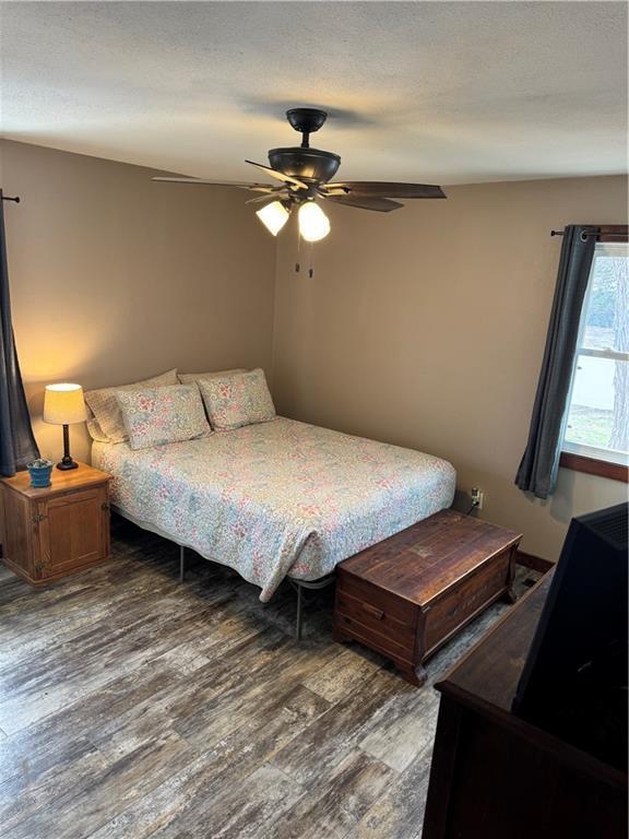 bedroom featuring ceiling fan, wood finished floors, and a textured ceiling