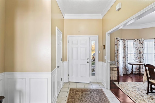 foyer entrance featuring ornamental molding, wainscoting, and light tile patterned flooring