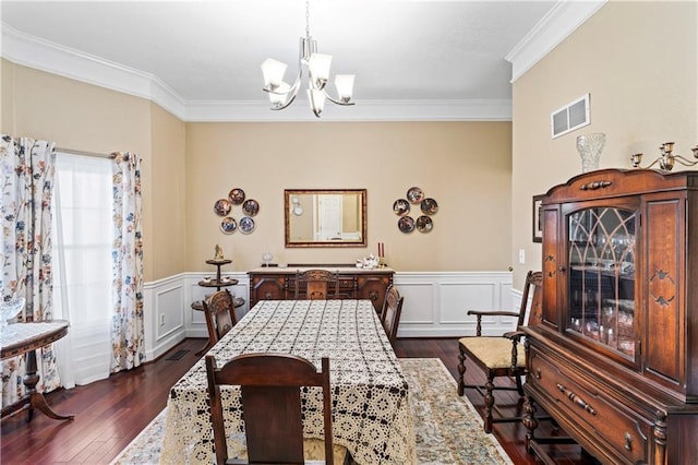 dining space featuring dark wood-style floors, visible vents, a notable chandelier, and ornamental molding