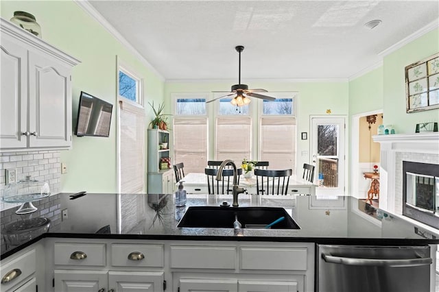 kitchen featuring plenty of natural light, dark countertops, a sink, and stainless steel dishwasher