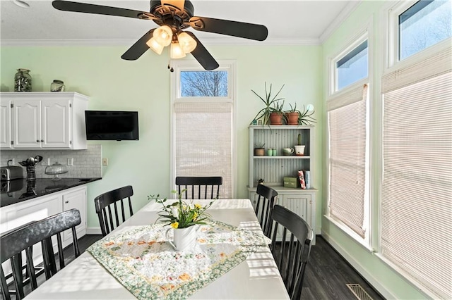 dining room with baseboards, visible vents, dark wood-style flooring, and crown molding