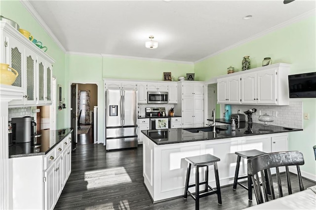 kitchen featuring a peninsula, a sink, white cabinetry, appliances with stainless steel finishes, and dark countertops