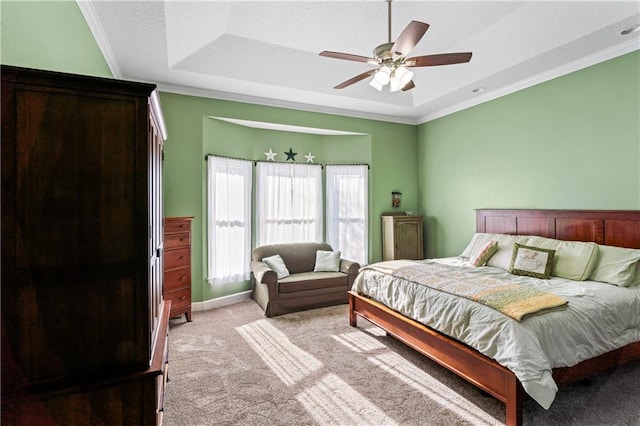 bedroom featuring carpet floors, a tray ceiling, crown molding, and baseboards