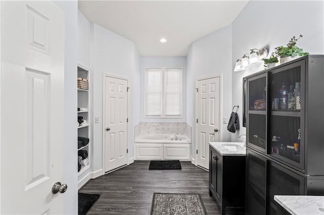 full bathroom with a closet, wood finished floors, vanity, a bath, and recessed lighting