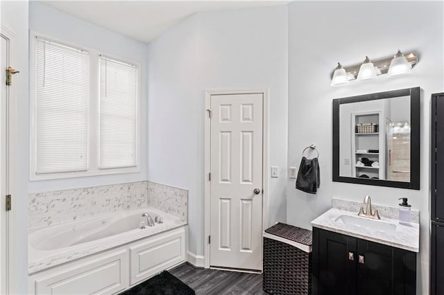 full bath with wood finished floors, a garden tub, and vanity