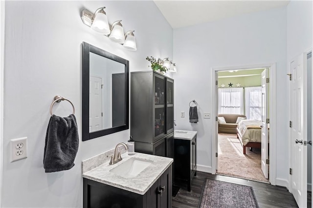 bathroom featuring wood finished floors, vanity, baseboards, and ensuite bathroom