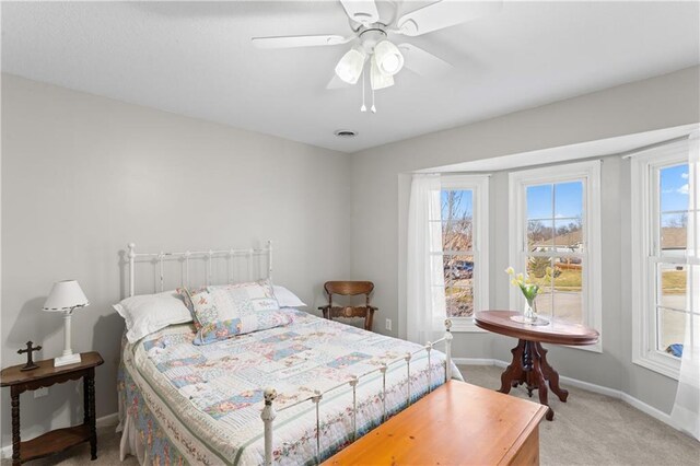 bedroom with baseboards, multiple windows, a ceiling fan, and light colored carpet