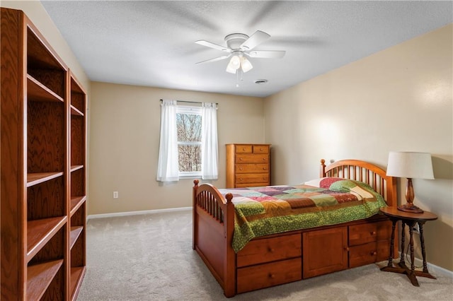 carpeted bedroom with ceiling fan, a textured ceiling, and baseboards