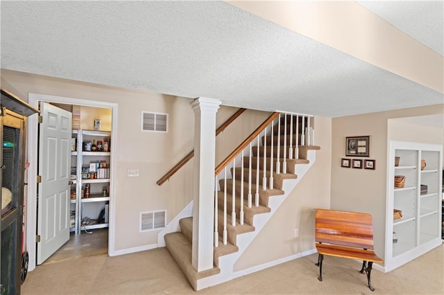 stairs with carpet floors, visible vents, and a textured ceiling