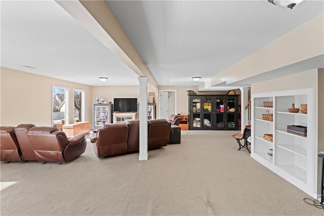 carpeted living room with decorative columns and a textured ceiling