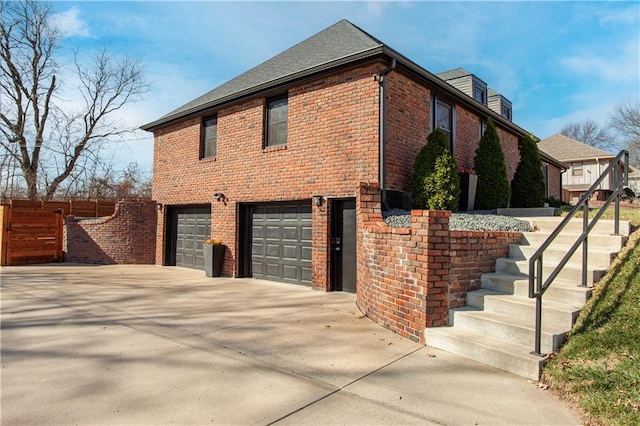 view of home's exterior featuring concrete driveway, fence, brick siding, and a garage