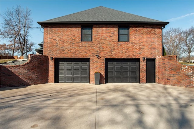 view of side of home featuring an attached garage, driveway, and a shingled roof