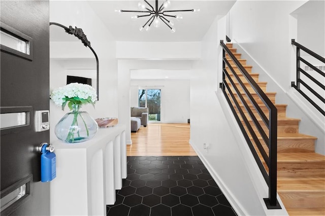 entrance foyer with baseboards, a notable chandelier, dark tile patterned floors, and stairs