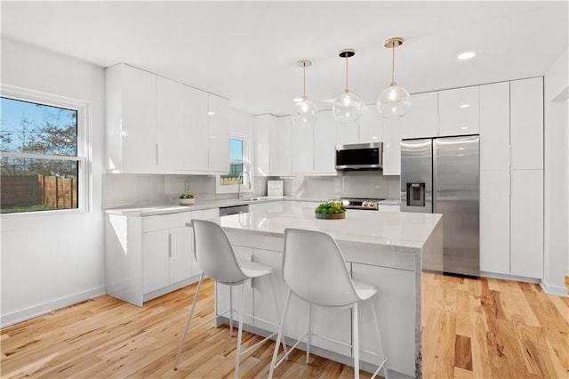 kitchen featuring modern cabinets, a kitchen island, appliances with stainless steel finishes, white cabinets, and decorative backsplash