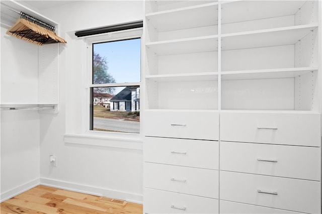 walk in closet with light wood finished floors