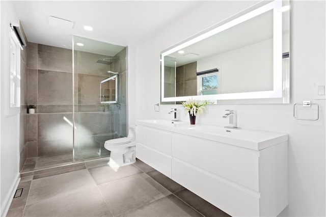 bathroom with double vanity, a tile shower, a sink, tile patterned flooring, and toilet