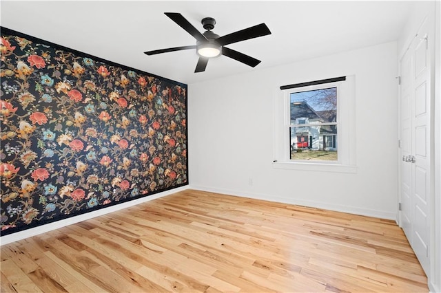 empty room featuring baseboards, a ceiling fan, and wood finished floors