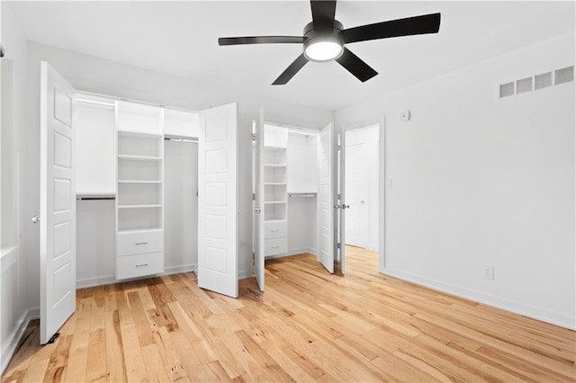 unfurnished bedroom featuring visible vents, two closets, baseboards, ceiling fan, and light wood-style flooring