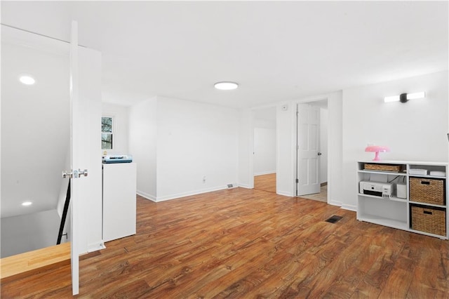 below grade area featuring wood finished floors, visible vents, and baseboards