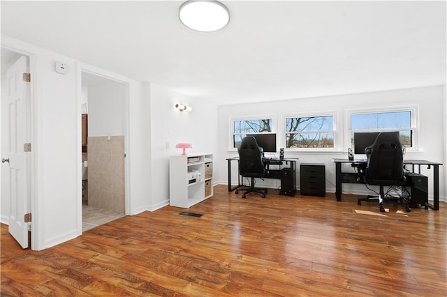 office space with wood finished floors, visible vents, and baseboards