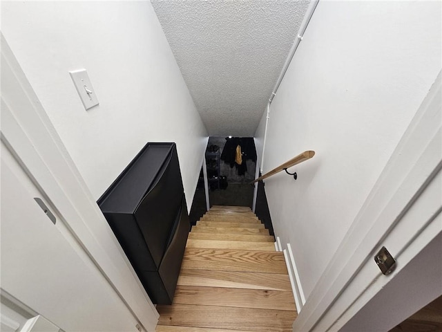 stairs with a textured ceiling and wood finished floors