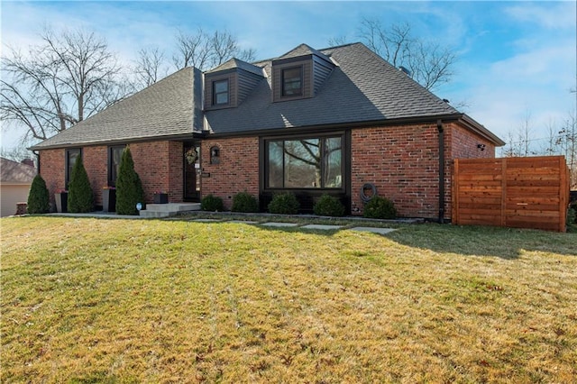 view of front of property featuring brick siding, a front lawn, and fence