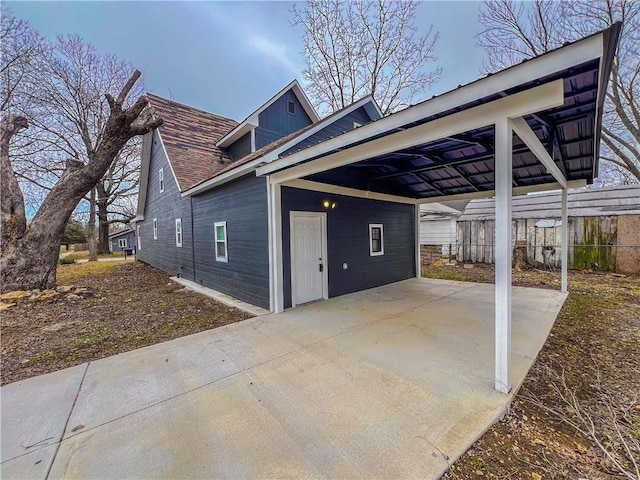 view of side of property featuring a carport, concrete driveway, and fence