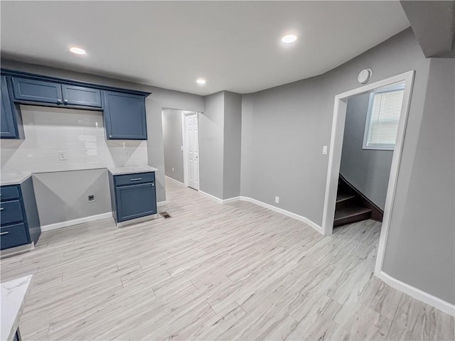 below grade area with light wood finished floors, stairway, recessed lighting, and baseboards