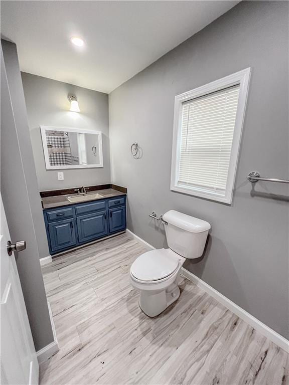 bathroom featuring wood finished floors, vanity, toilet, and baseboards