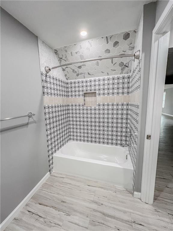 bathroom featuring shower / bath combination and baseboards