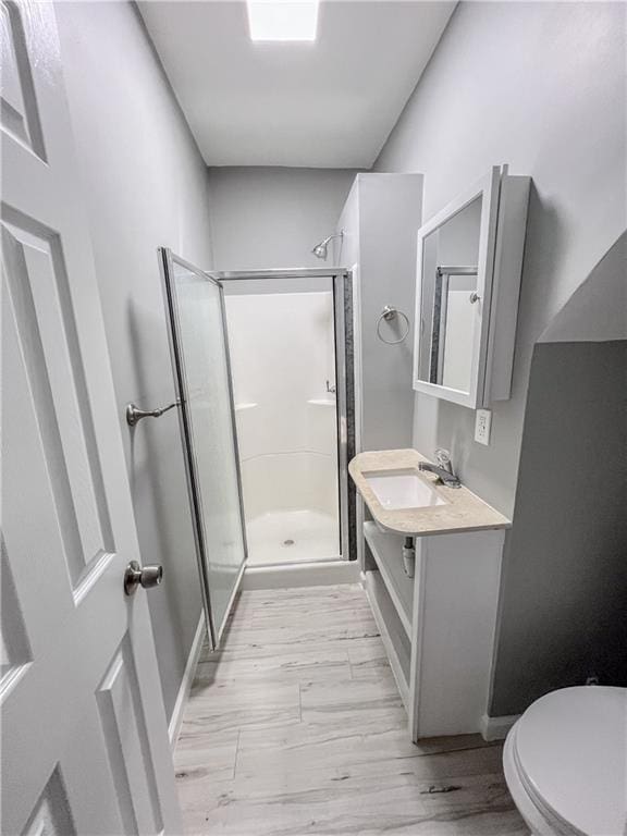 full bathroom with baseboards, toilet, wood finished floors, vanity, and a shower stall