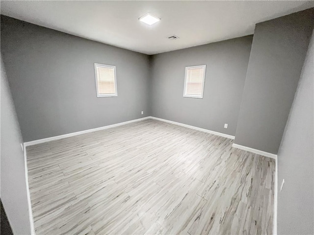 spare room featuring baseboards and wood finished floors