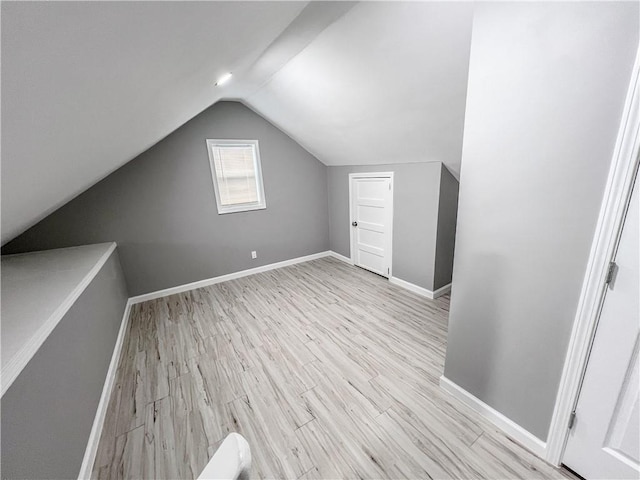 bonus room with light wood-type flooring, lofted ceiling, and baseboards