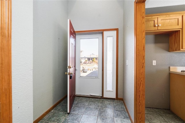 foyer entrance featuring dark tile patterned floors and baseboards