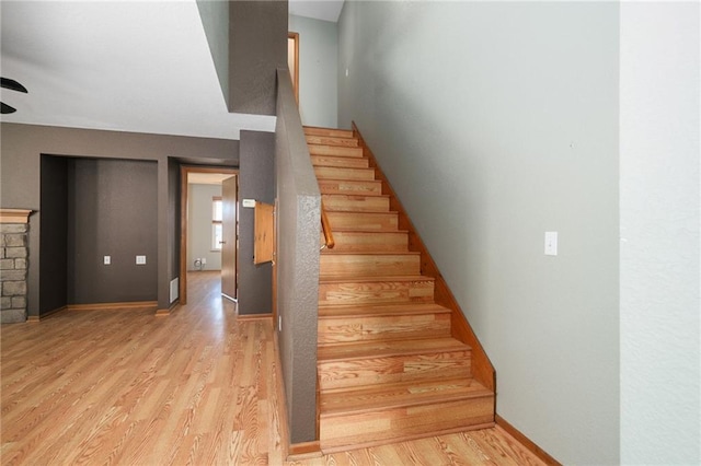 staircase with a fireplace, baseboards, and wood finished floors