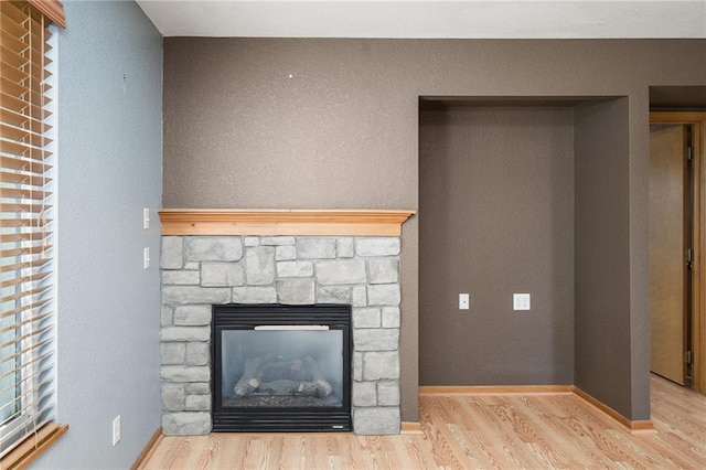 details with a stone fireplace, baseboards, and wood finished floors