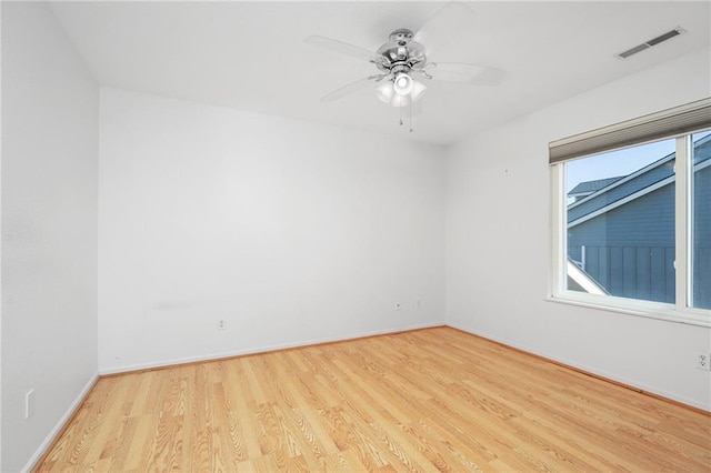 unfurnished room with a ceiling fan, wood finished floors, visible vents, and baseboards