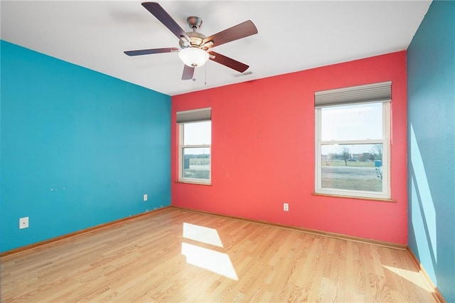 empty room featuring a ceiling fan, wood finished floors, and visible vents