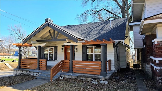 bungalow-style home with a porch and roof with shingles