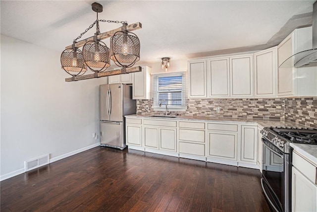 kitchen featuring visible vents, a sink, dark wood-type flooring, appliances with stainless steel finishes, and wall chimney exhaust hood