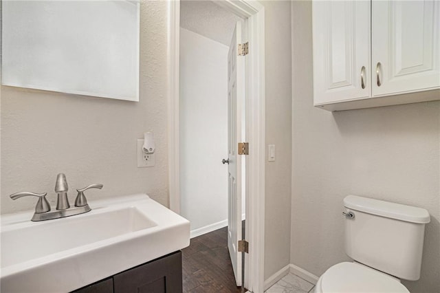 bathroom with baseboards, toilet, wood finished floors, and vanity