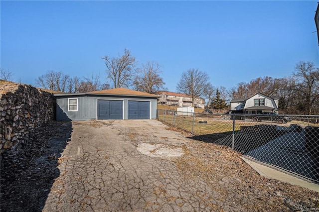 view of yard featuring aphalt driveway, an outdoor structure, a garage, and fence