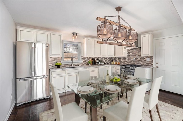 kitchen featuring wood finished floors, a sink, white cabinets, appliances with stainless steel finishes, and backsplash
