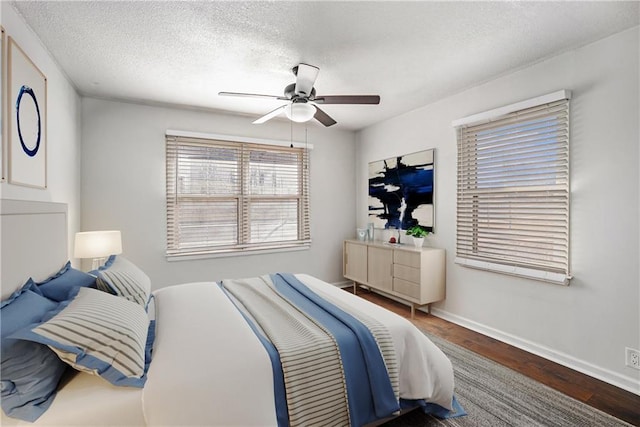 bedroom with baseboards, a textured ceiling, wood finished floors, and a ceiling fan