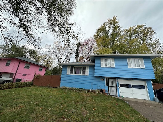 tri-level home with a garage, a front yard, driveway, and fence