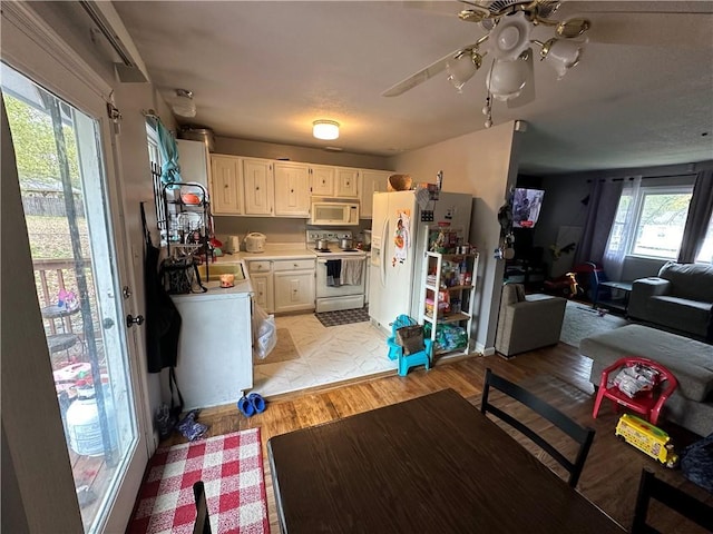 kitchen with open floor plan, light wood-type flooring, light countertops, white appliances, and a ceiling fan