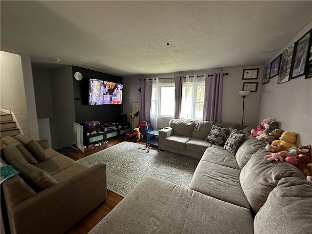 living room with stairway, a textured ceiling, and dark wood-style flooring
