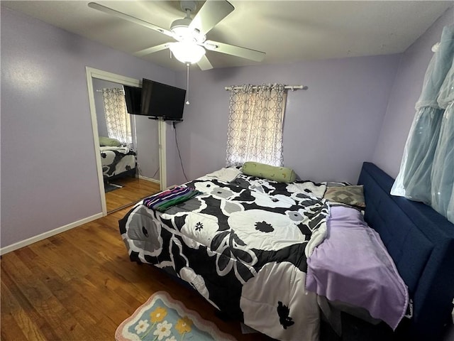 bedroom with a closet, baseboards, wood finished floors, and a ceiling fan